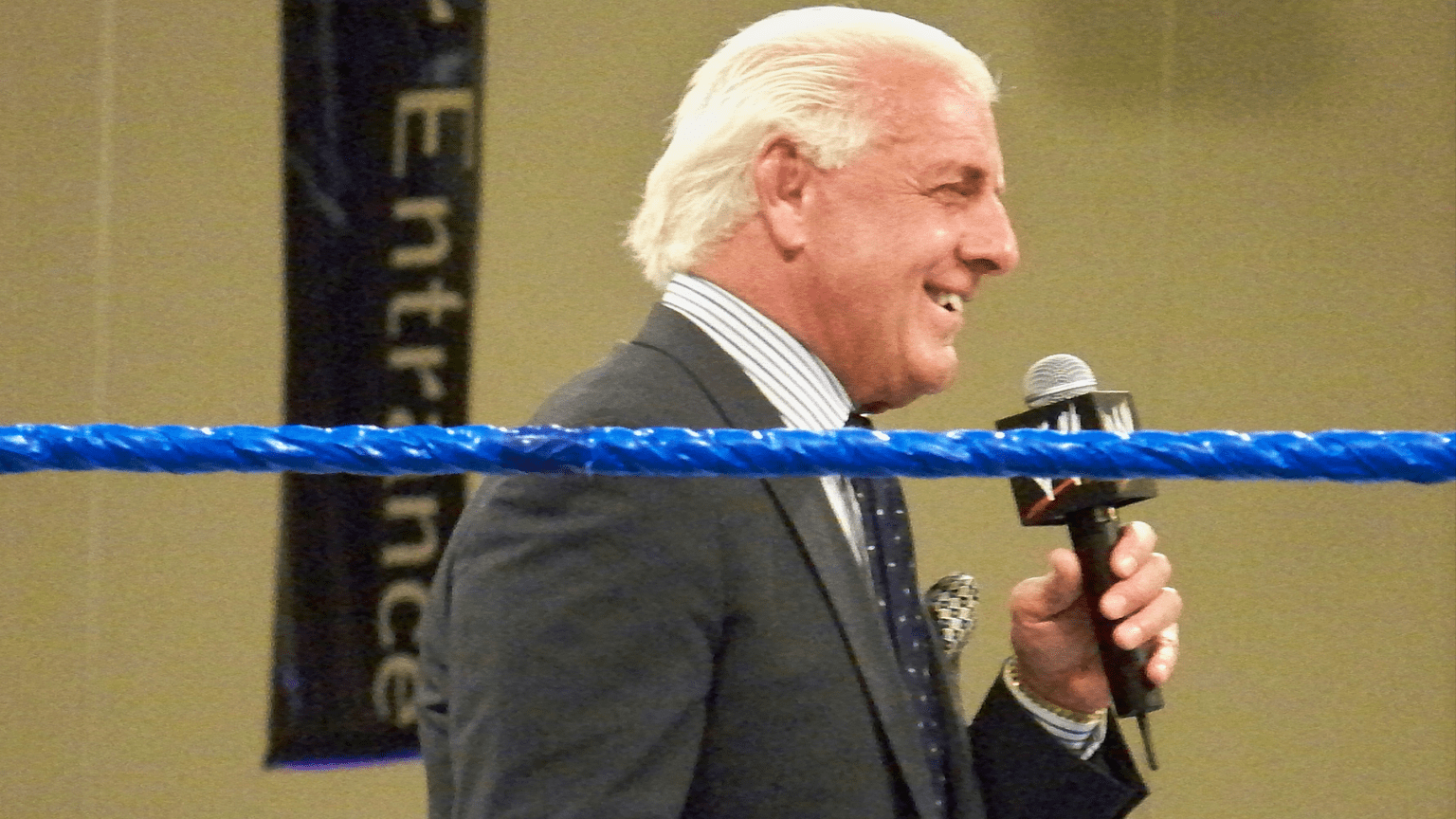 Ric Flair standing in the ring holding a WWE microphone.